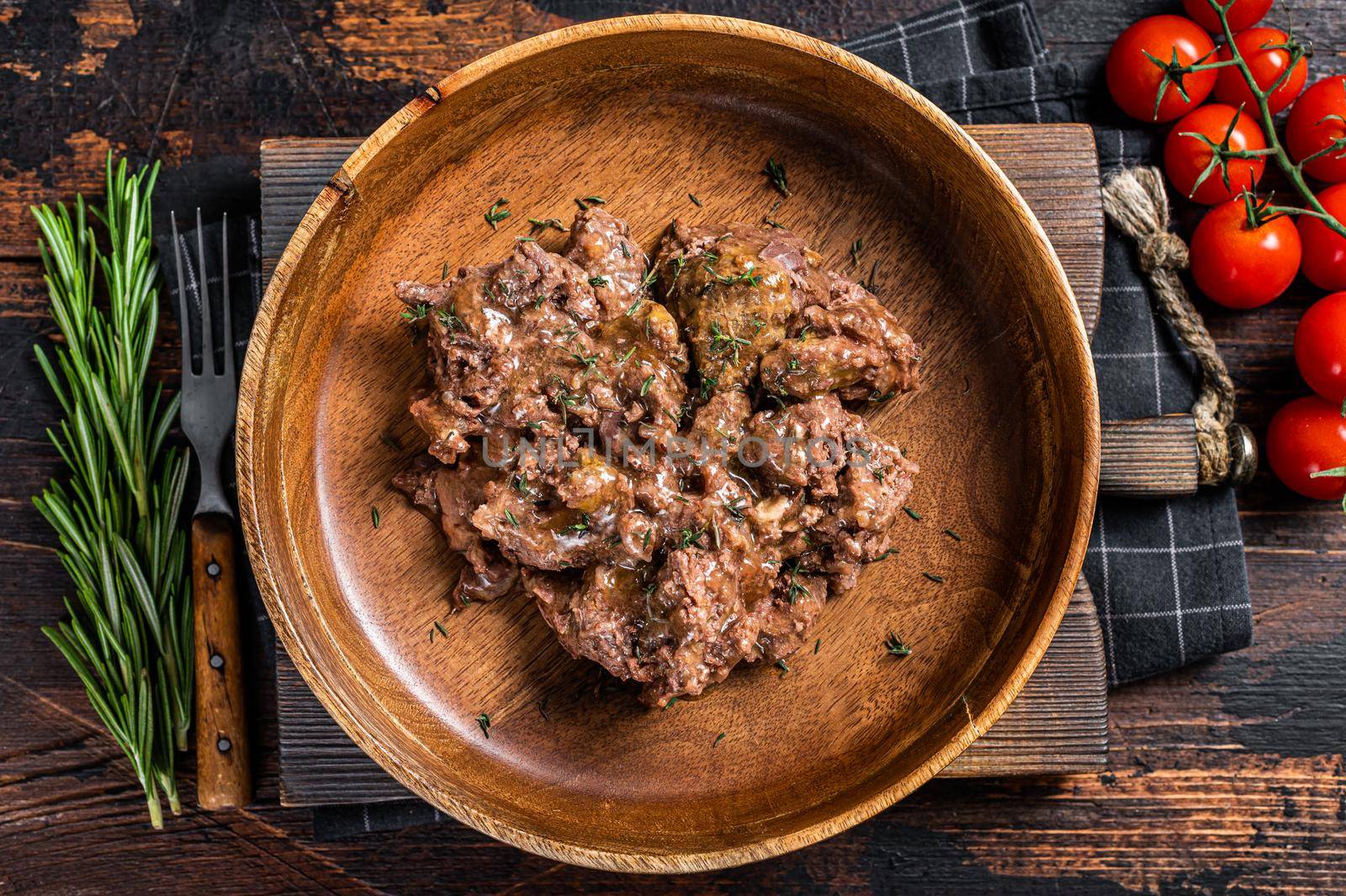 Stewed beef meat in a wooden plate. Dark Wooden background. Top view by Composter