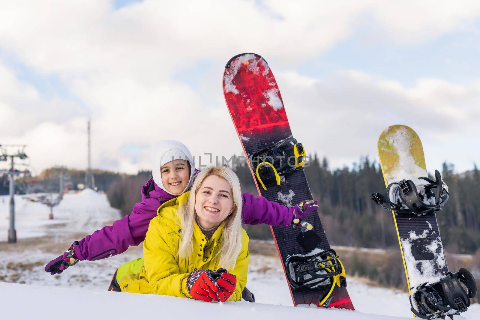 mother and daughter with snowboards in a mountain resort