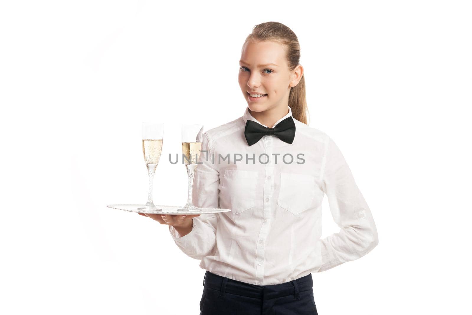 Smiling waitress in uniform holding tray with two glasses of champagne