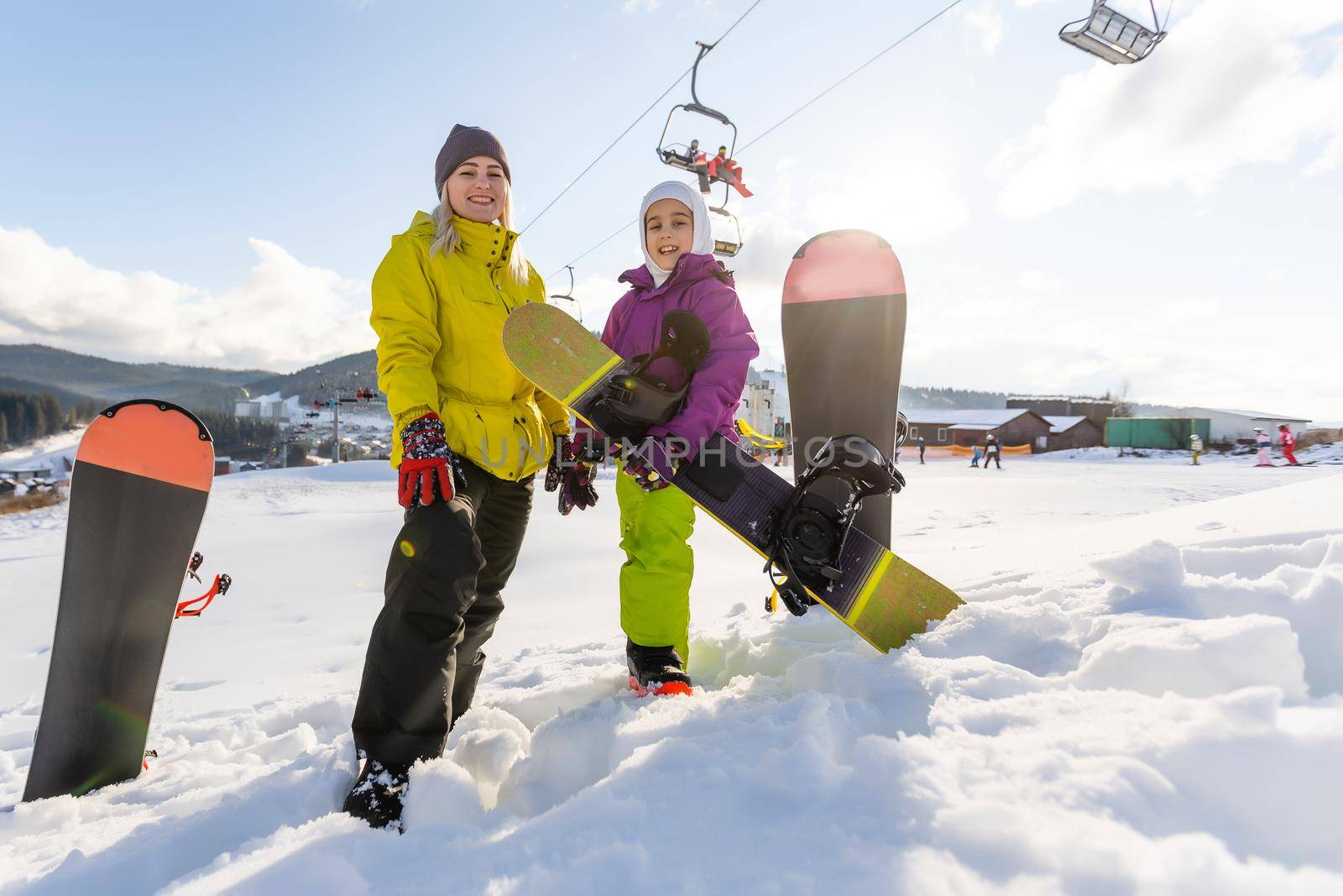 Mother and daughter with snowboards are playing in the snow