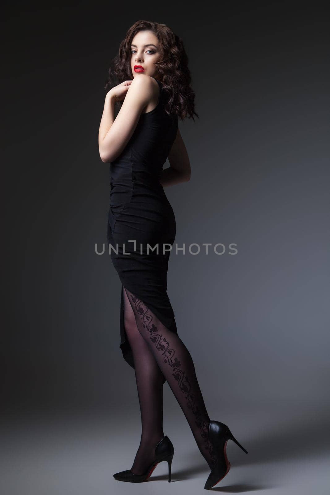 Gorgeous young woman posing in black dress and looking at camera.
