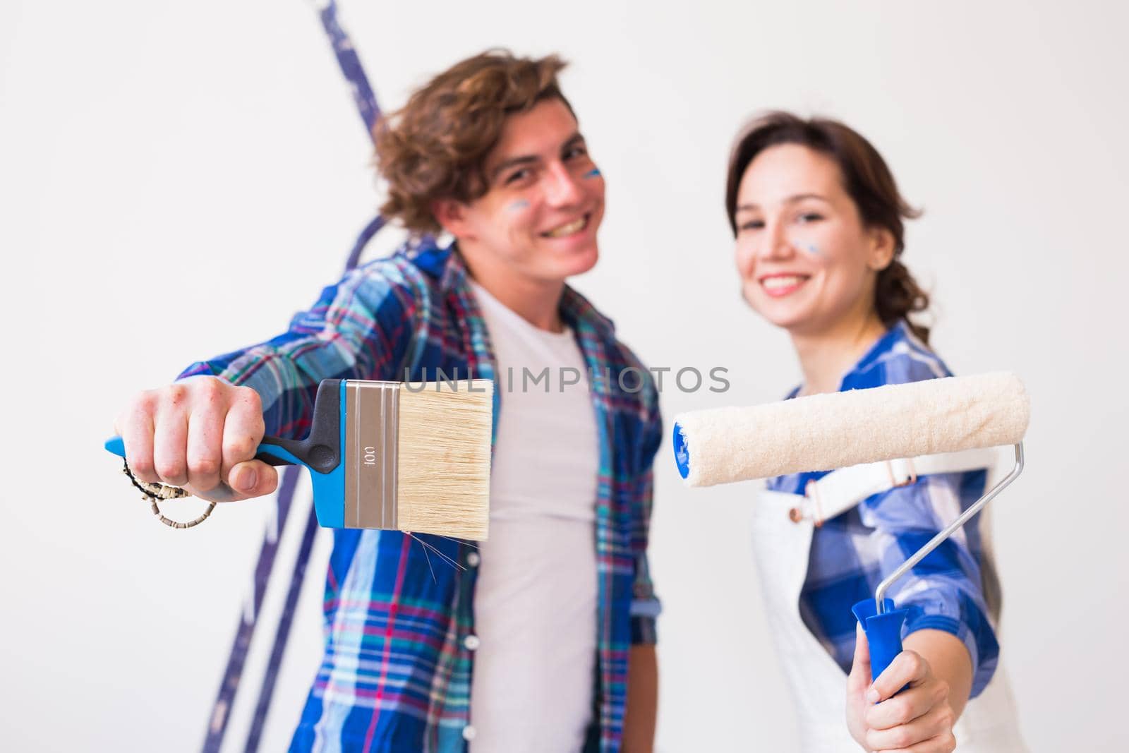 Teamwork, renovation and repair concept - Portrait of funny couple doing redecoration in apartment.
