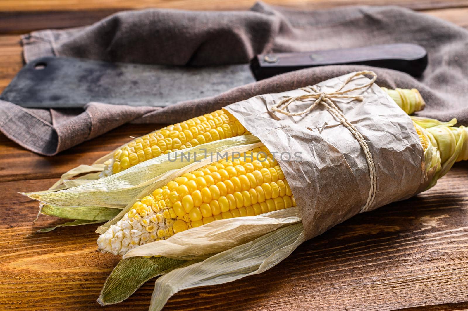 Fresh harvested corn cob on farmer market, local vegetables. Wooden background. Top view by Composter