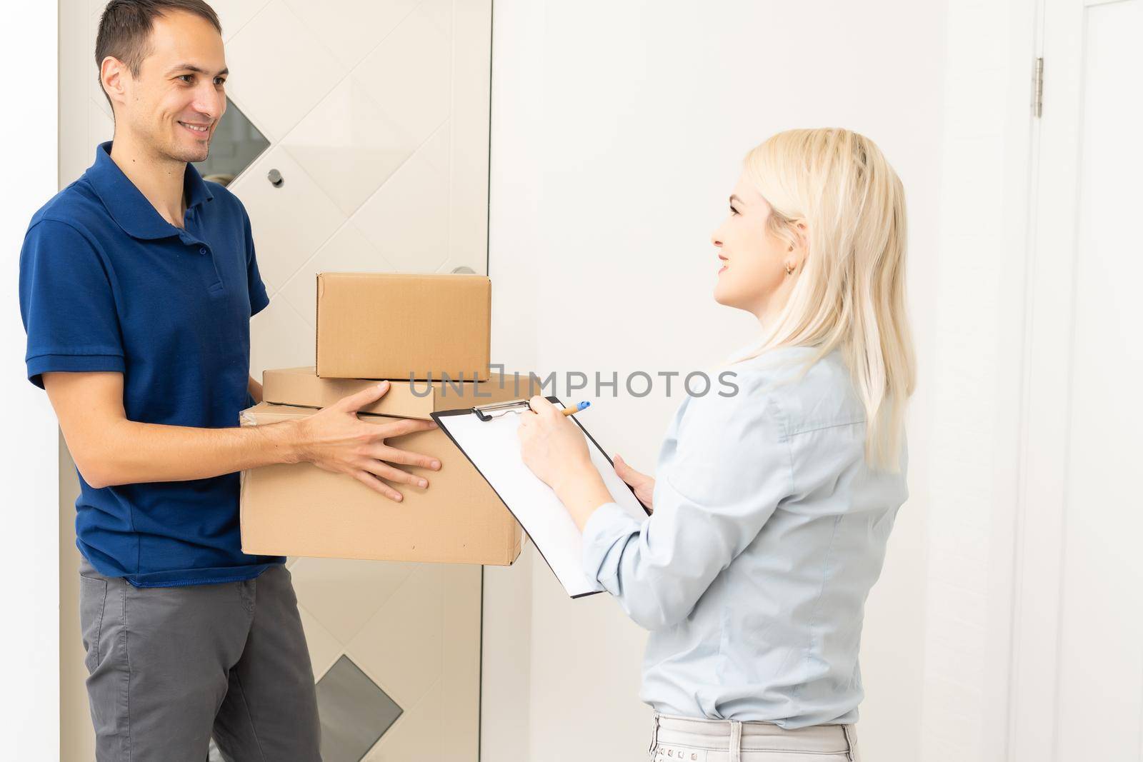 woman receiving boxes from postman at the door in home delivery concept. Woman received the parcel from the postman at home. Postman giving cardboard box to young woman.