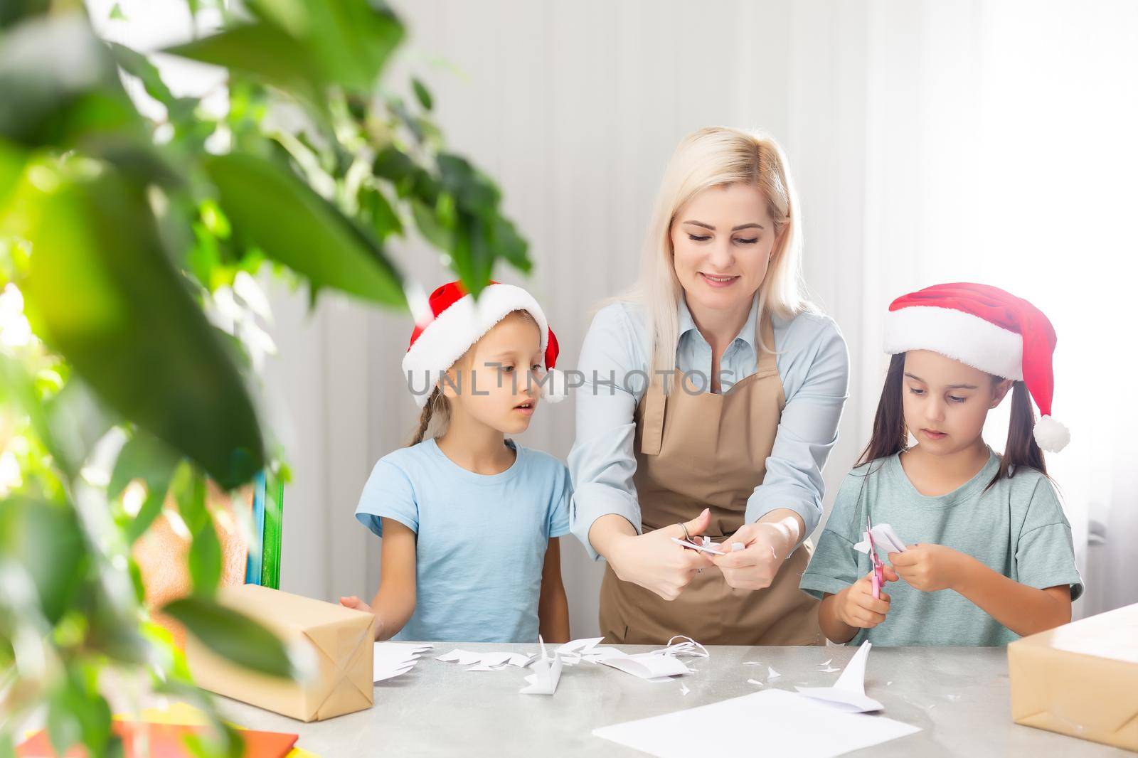 woman and two daughters carve snowflakes for christmas. Technology and Education Caucasian Blonde Family concept by Andelov13