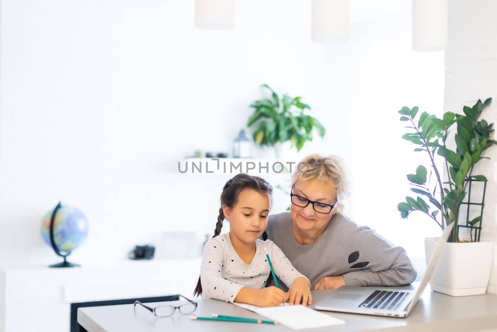 Helpful granny. Helpful loving granny assisting her cute granddaughter making homework by Andelov13