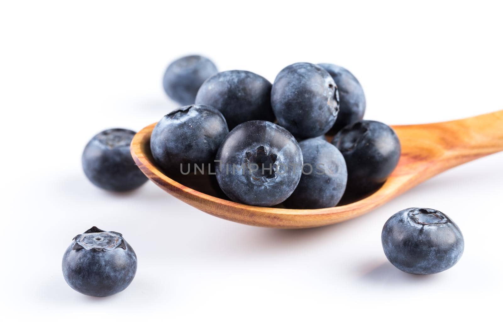 Fresh blueberries in wooden spoon on white background