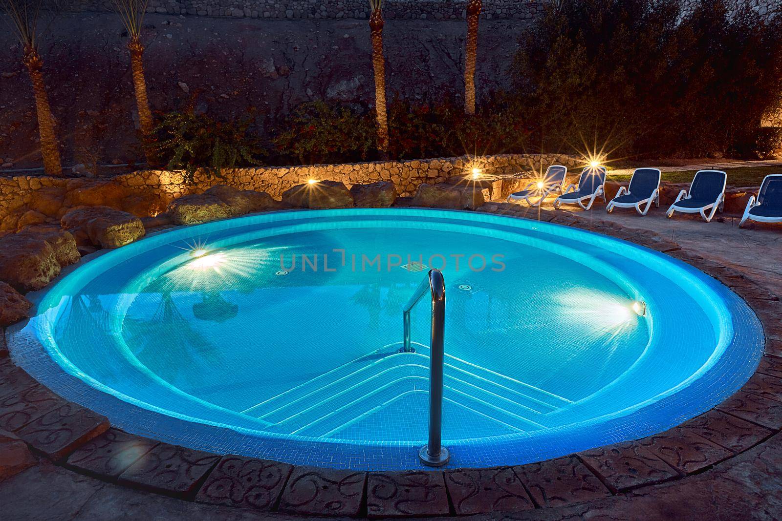 Elegant empty water pool with blue water at night. Resort, SPA complex