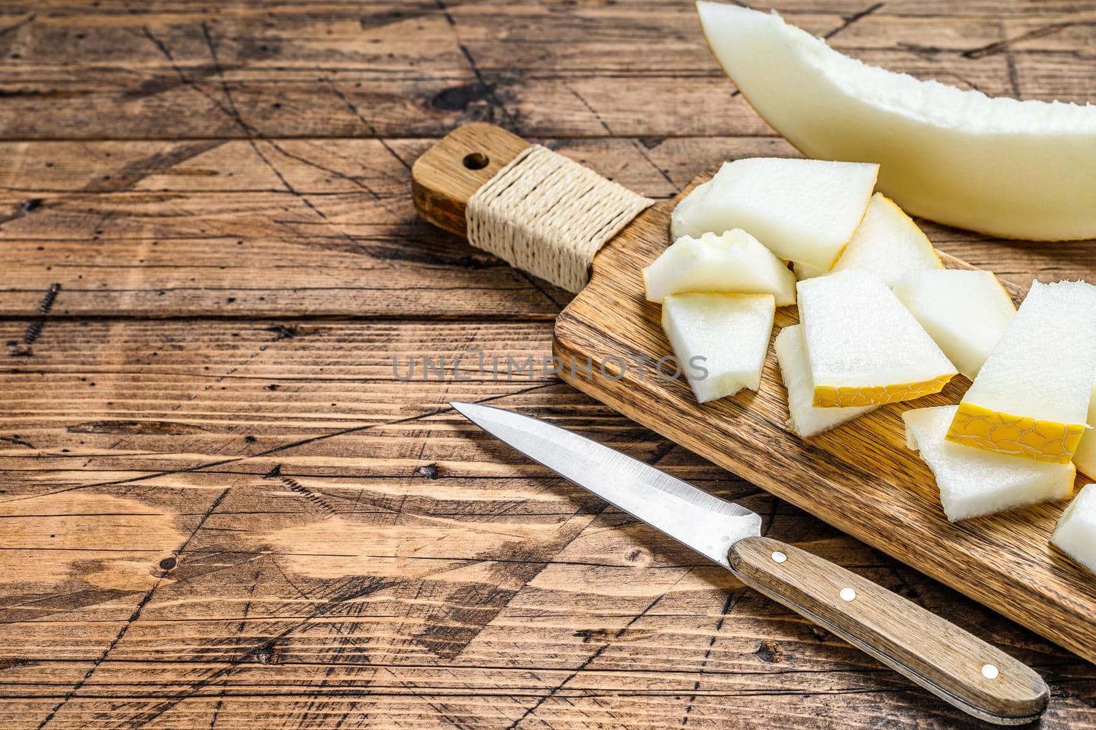 Slices of yellow melon on the cutting Board. wooden background. Top view.