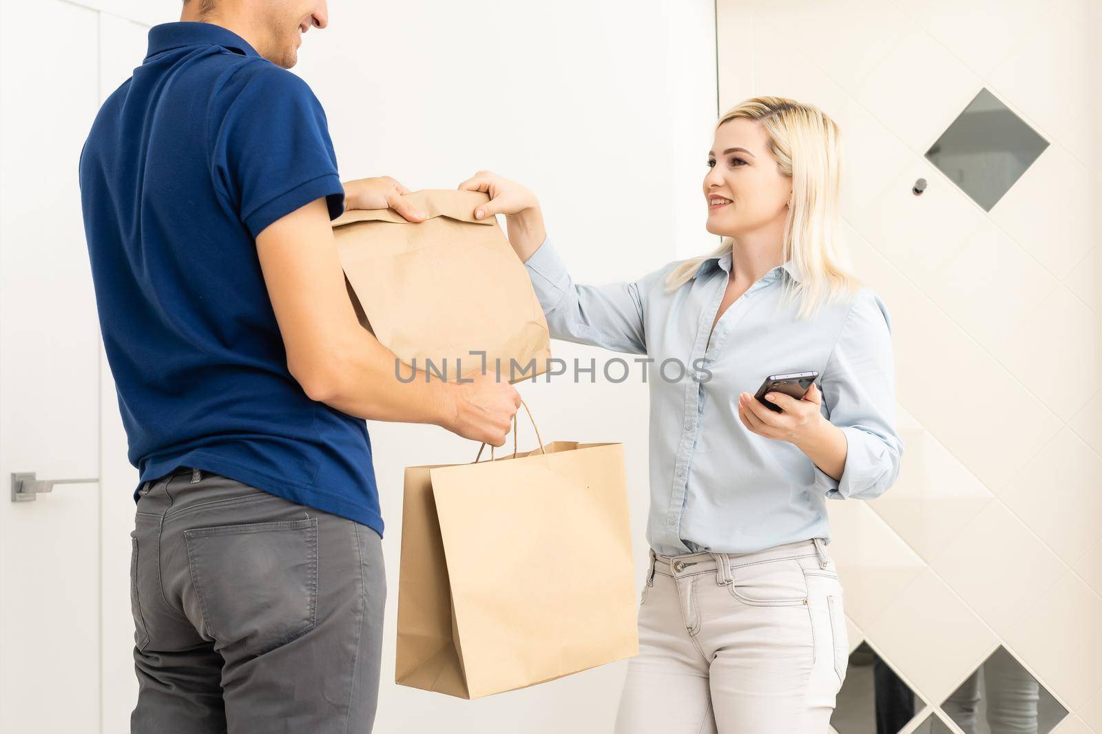 Woman and courier during order transfer. Woman accepting delivery from deliveryman. Cropped image of delivery service worker giving parcel to client.