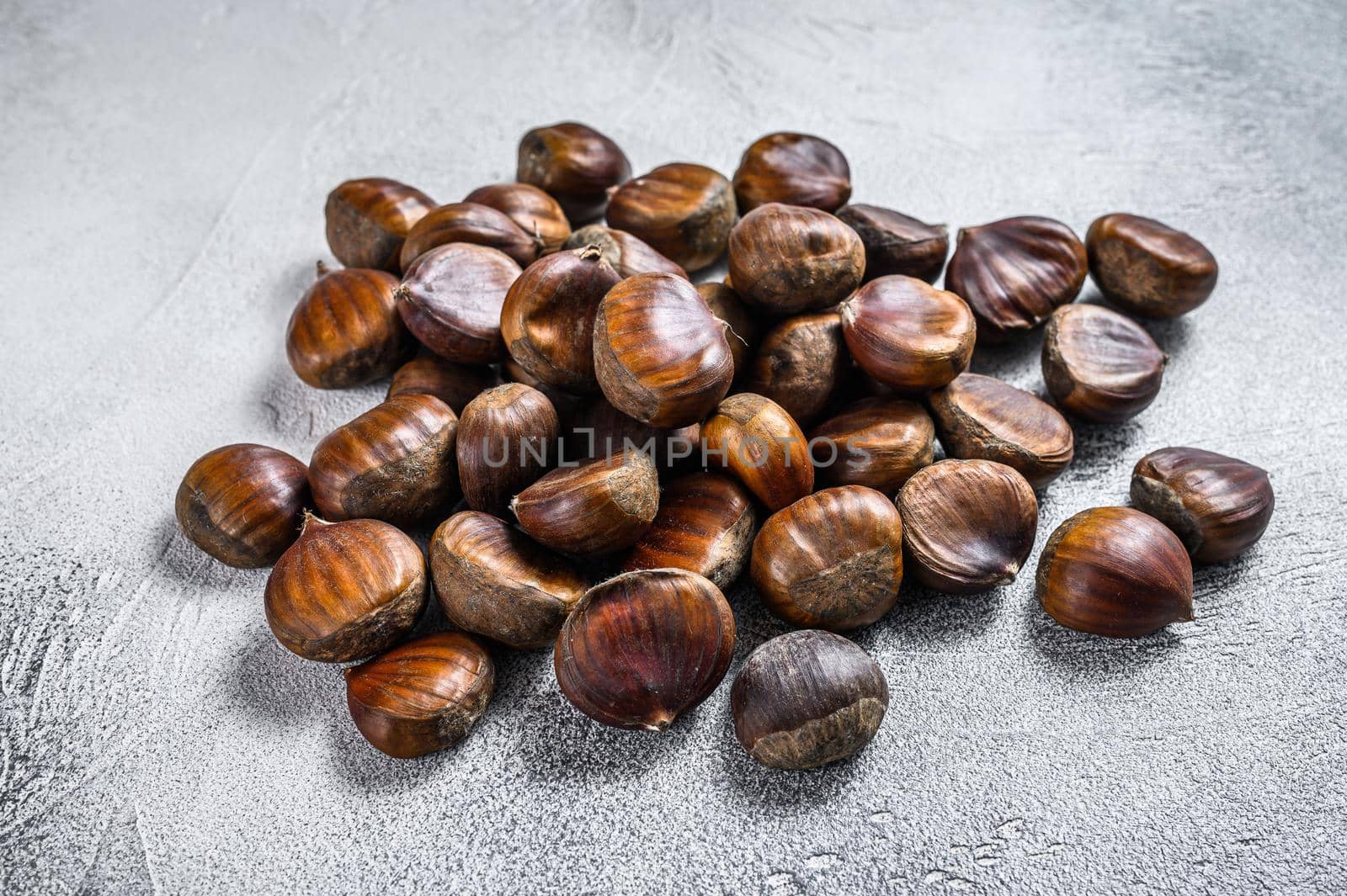 Raw chestnuts on a wooden table. White background. Top view by Composter