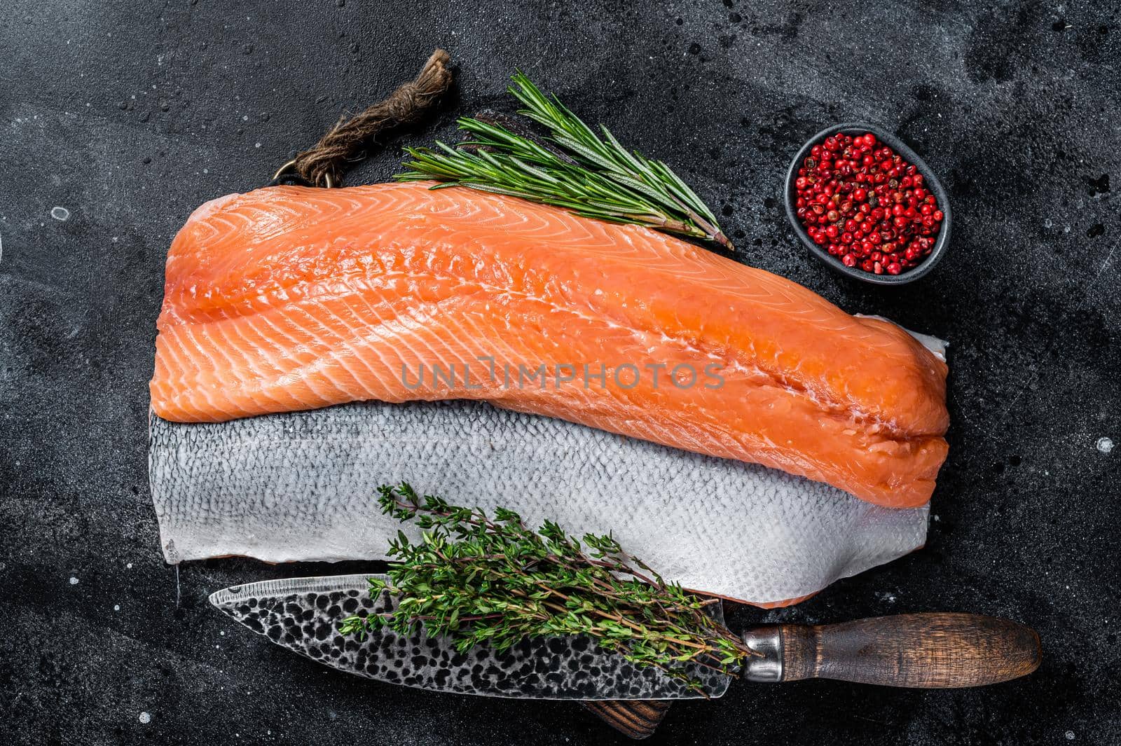 Fresh raw salmon fillet fish on cutting board with knife. Black background. Top view by Composter