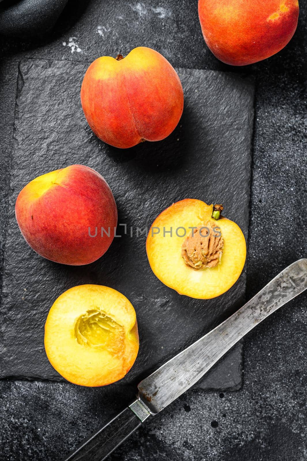 Organic Peaches fruit on a black stone Board. Black background. Top view.