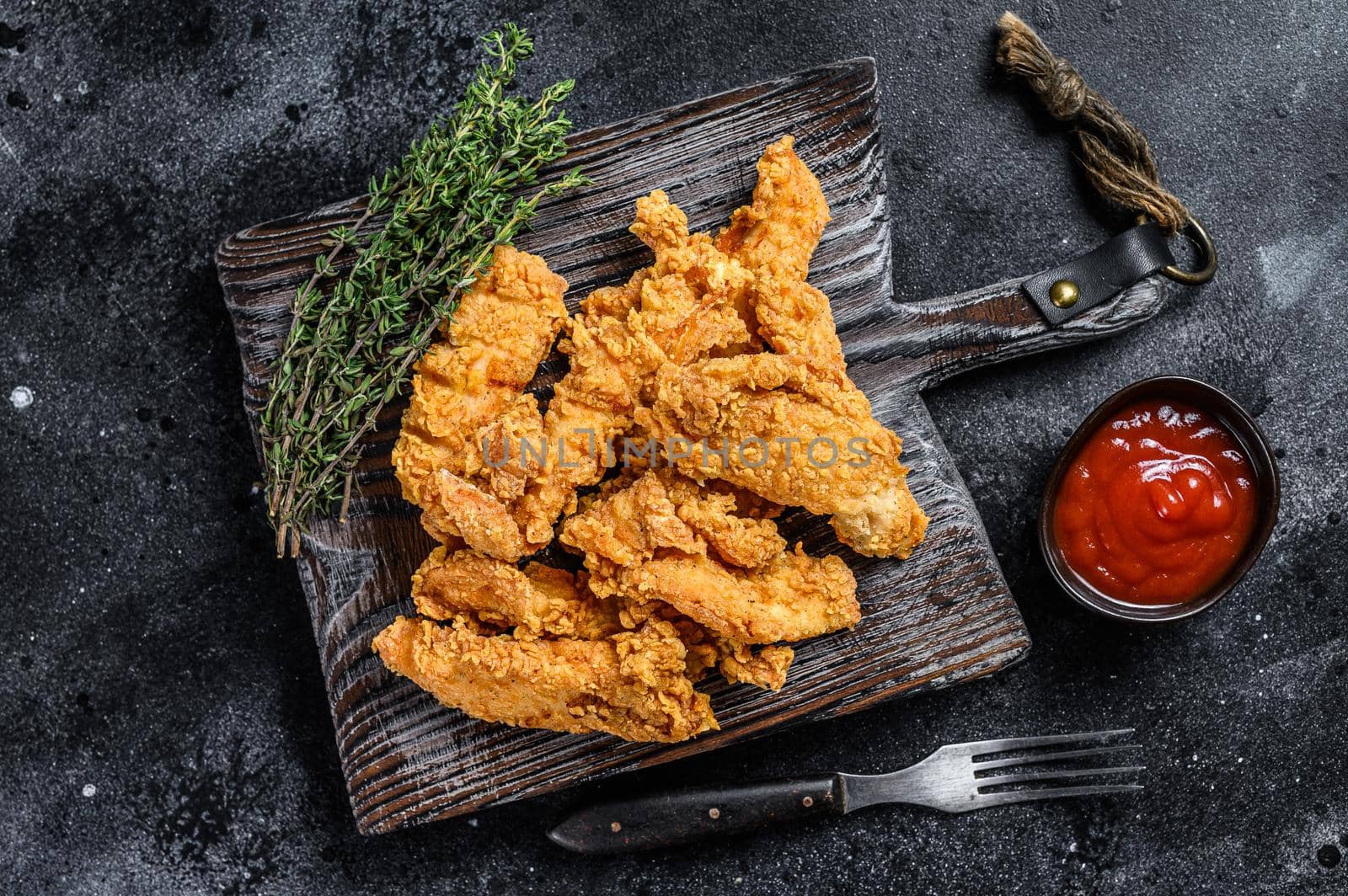 Steak Fingers fried breaded chicken breast strips. Black background. Top view by Composter
