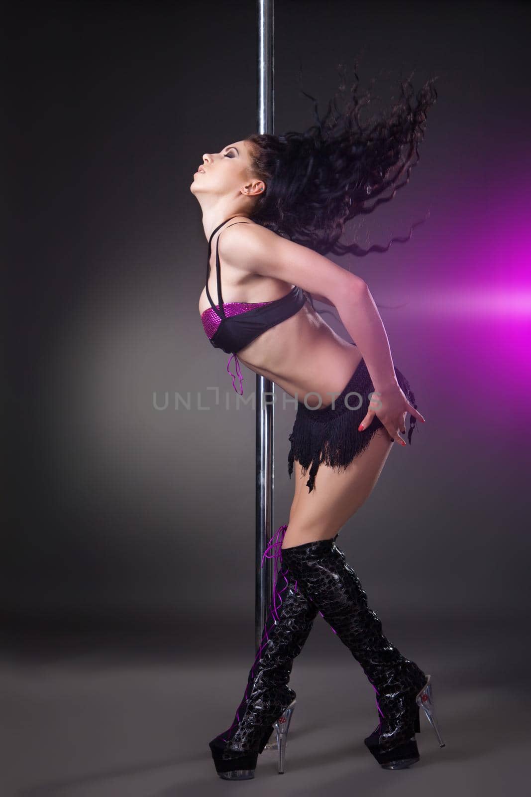 Young sexy woman exercise pole dance against grey background