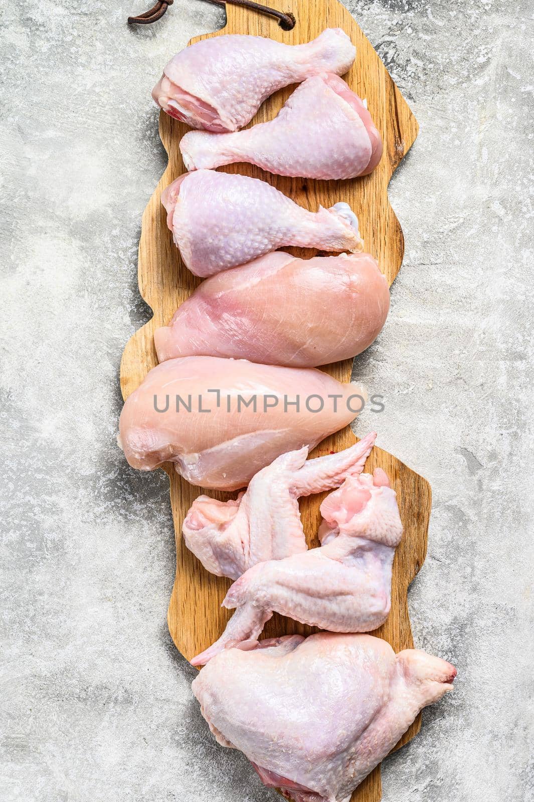 Raw uncooked chicken meat on a cutting board. Gray background. Top view.