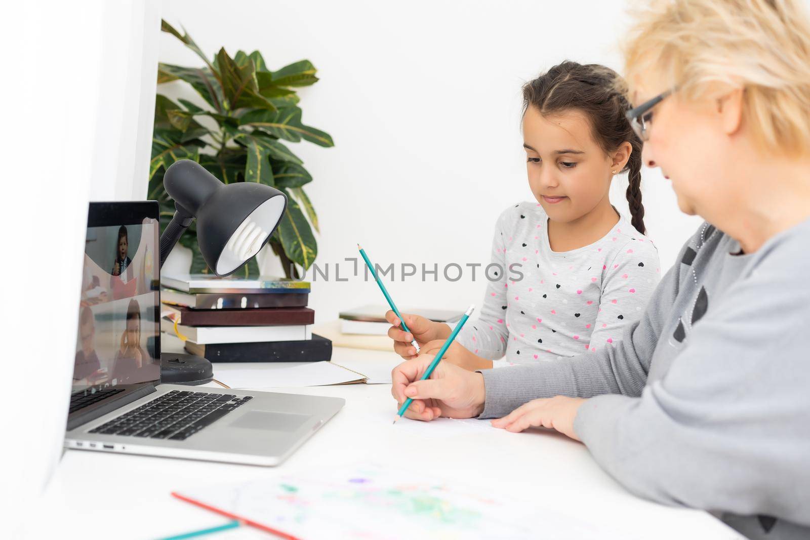 Helpful granny. Helpful loving granny assisting her cute granddaughter making homework by Andelov13