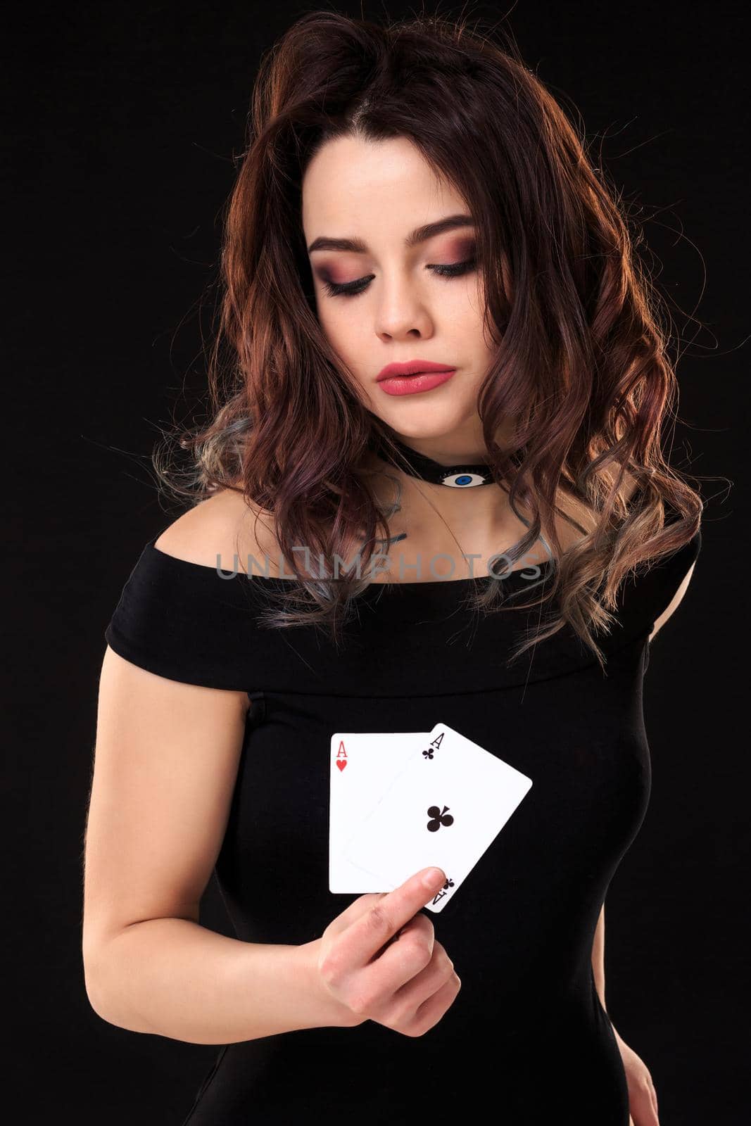 Young woman holding playing cards against a black background. Gambling. Poker. Two Aces.