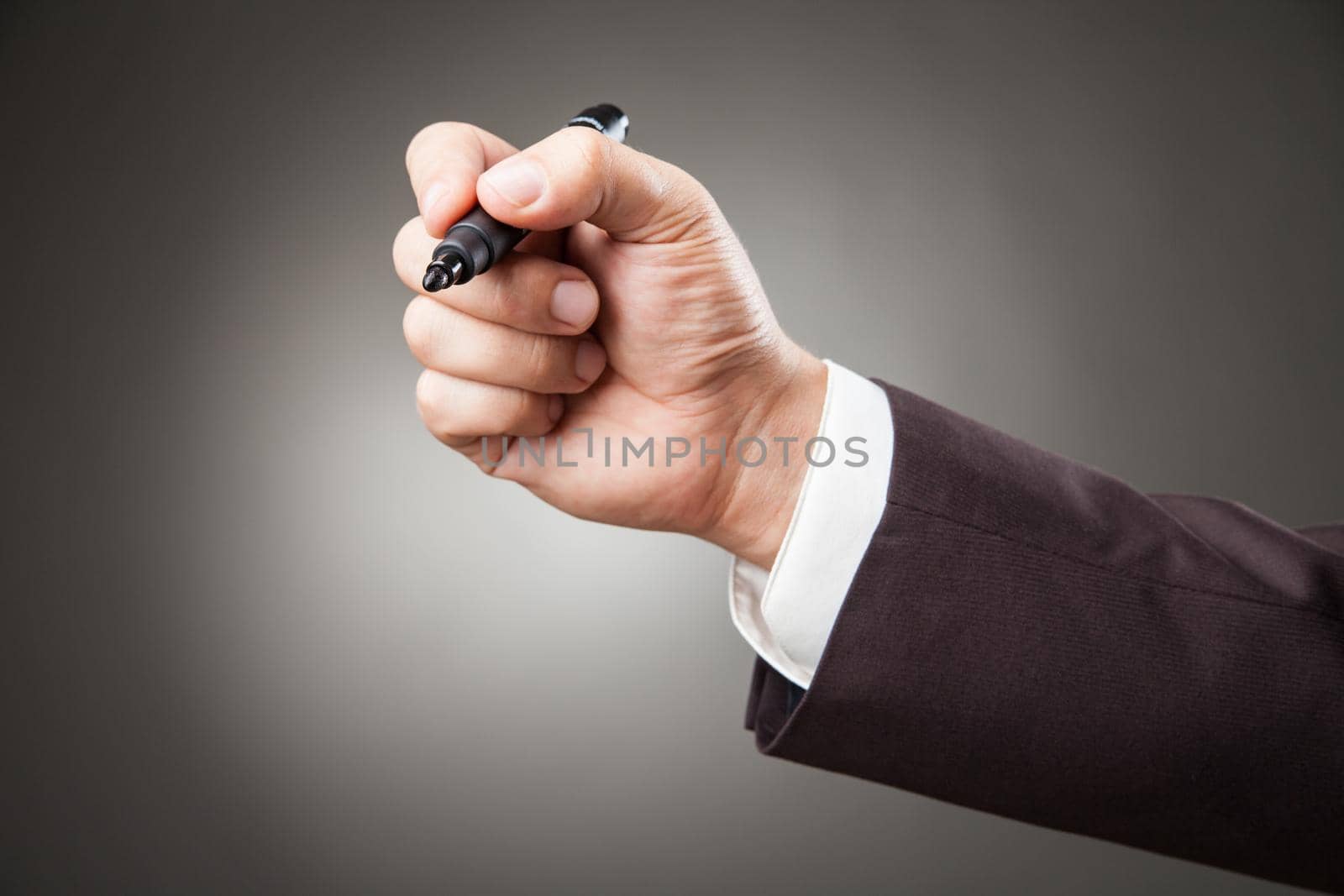 Hand of man wearing suit holding black marker. Horizontal studio shot