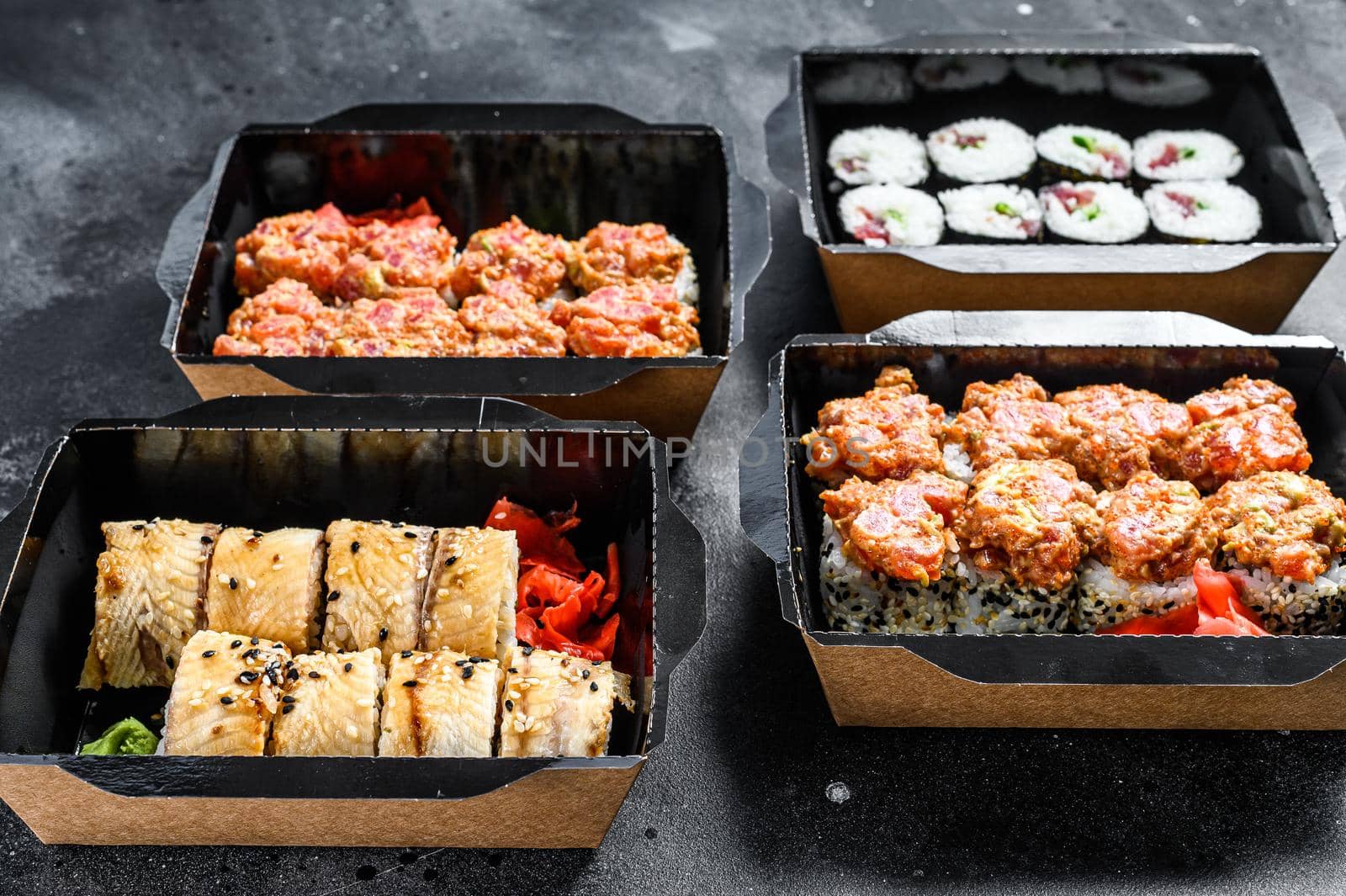 The sushi rolls in the delivery package, ordered in sushi take-out restaurant. Black background. Top view by Composter