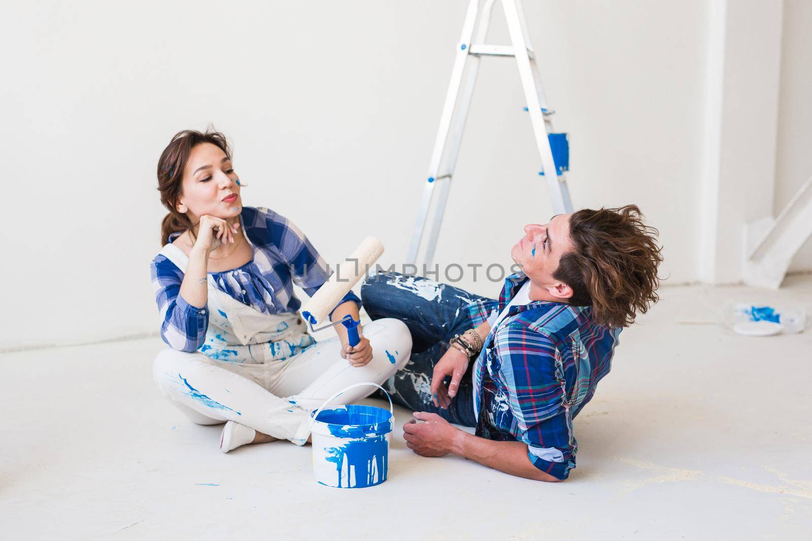 Renovation, redecoration and people concept - young couple doing a renovation in new home.