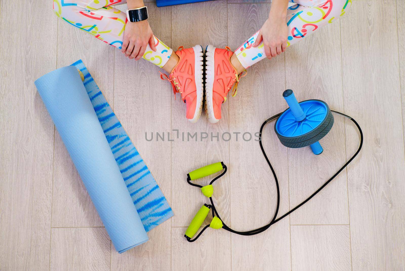 Flat lay of fitness and workout accessories, red dumbbells, water bottle and sneakers on wood background