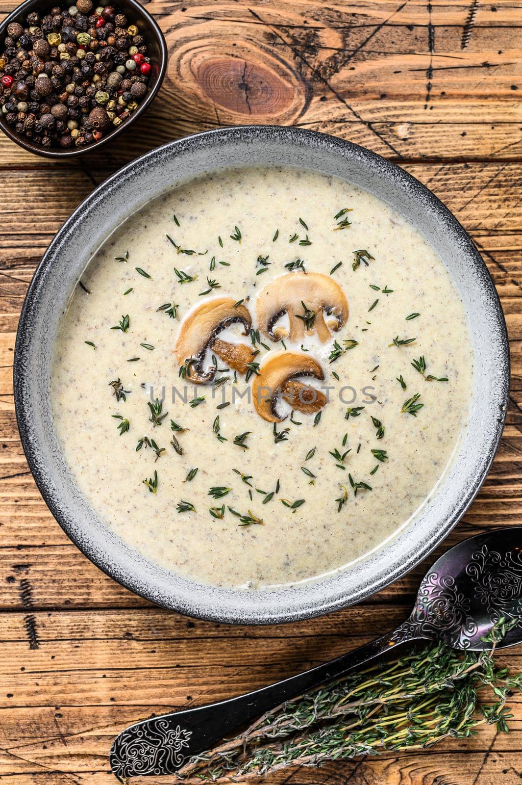Mushroom cream soup in a plate. Wooden background. Top view.