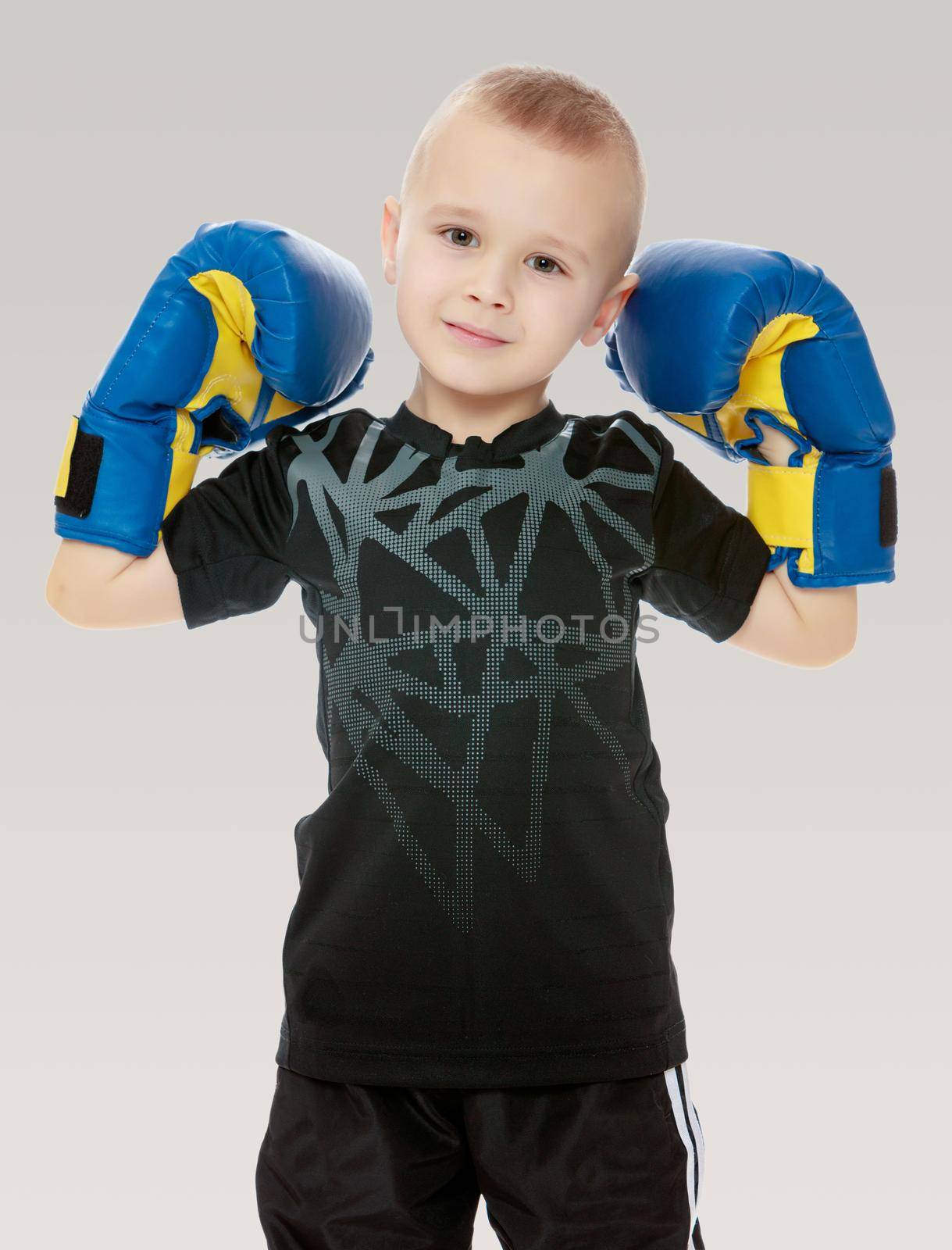 Cute little boy shows his Boxing gloves.On a gray background.