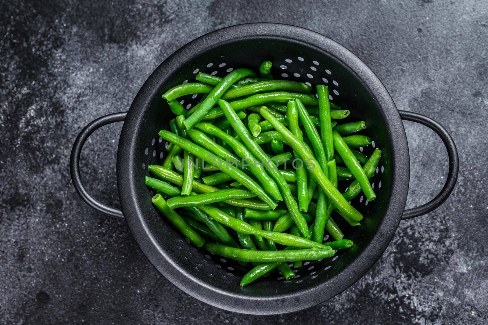 Raw green beans in a colander. Black background. top view by Composter