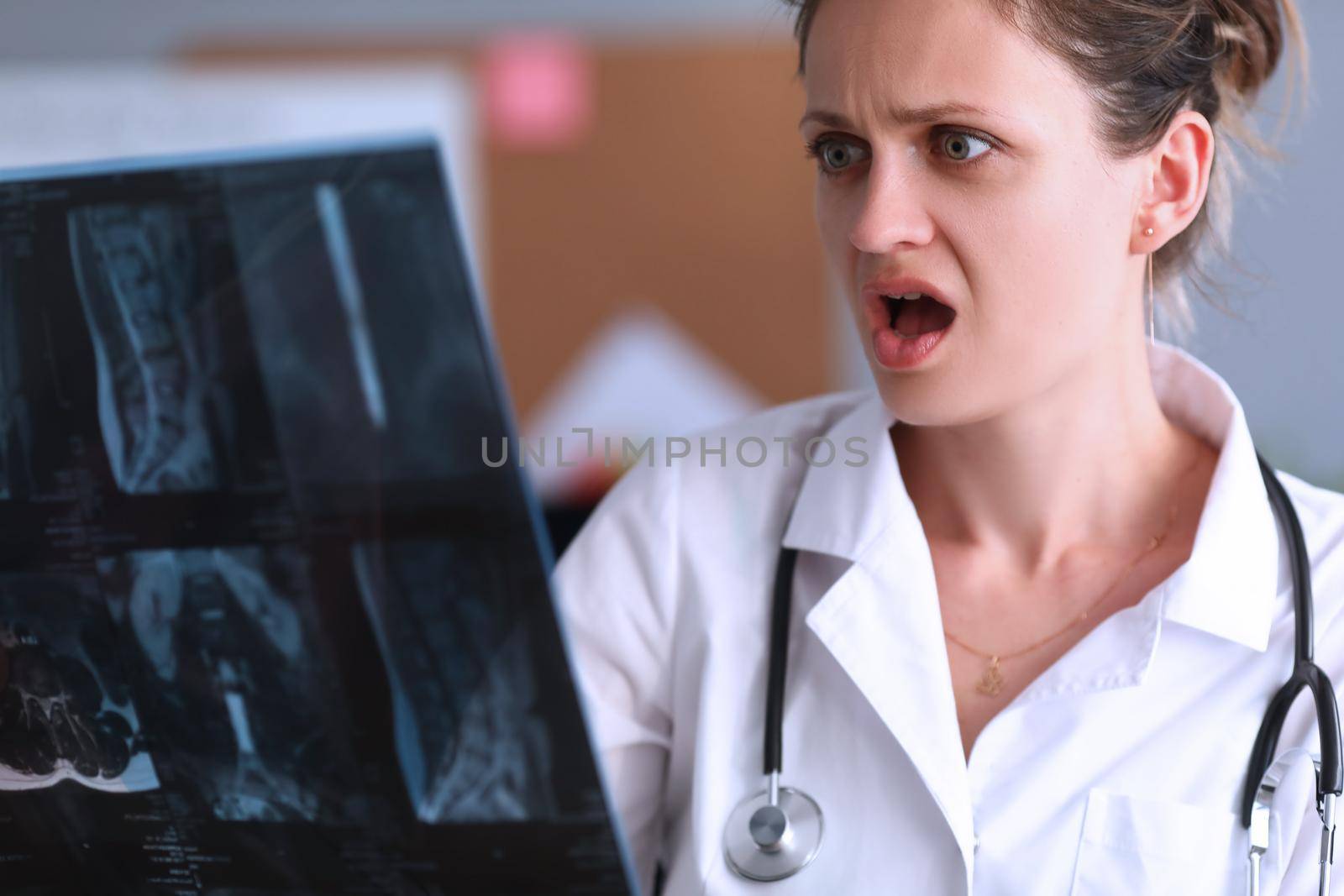 Shocked doctor looks at X-ray in clinic by kuprevich