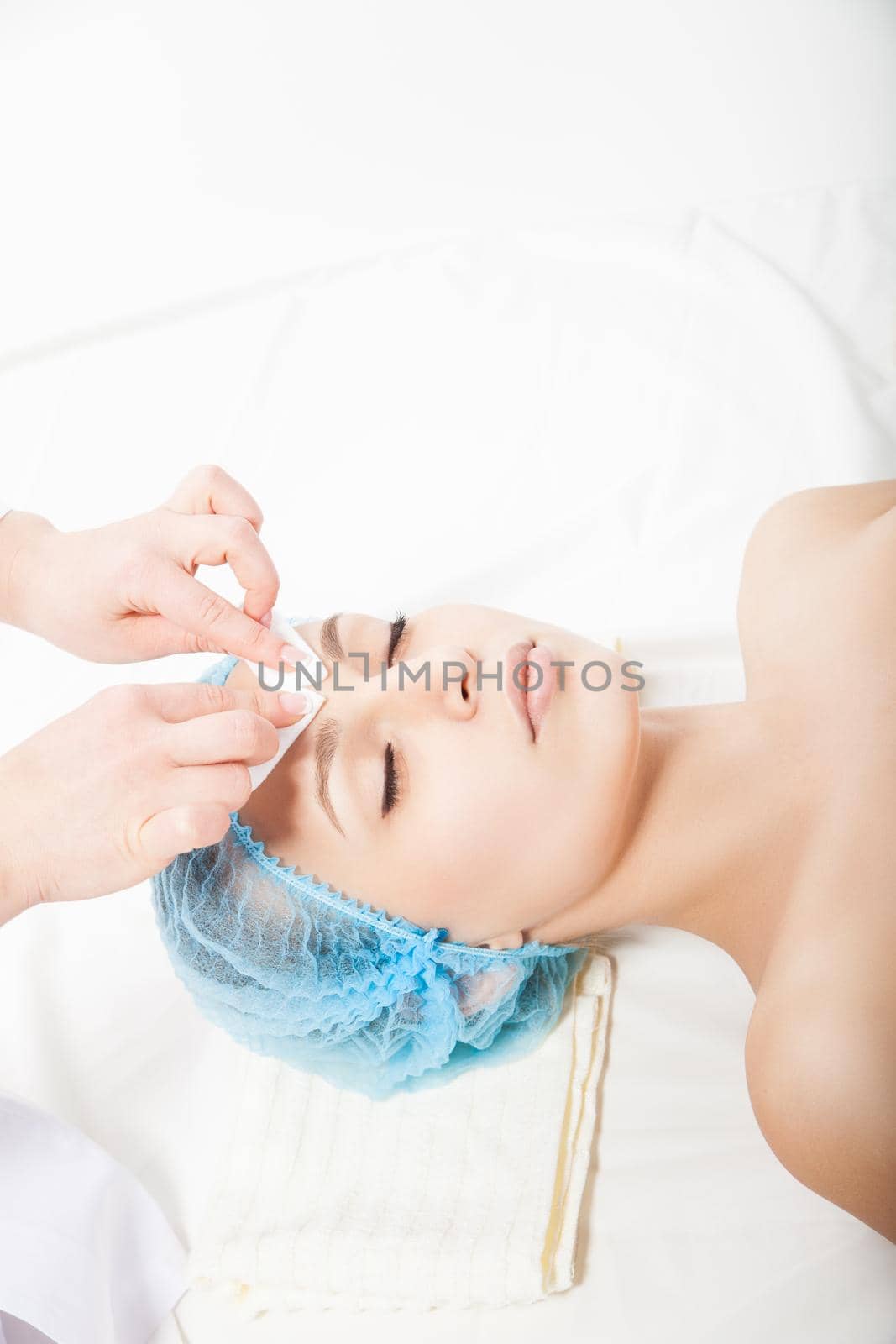 Woman laying at cosmetic procedure made by beautician. Vertical indoors shot