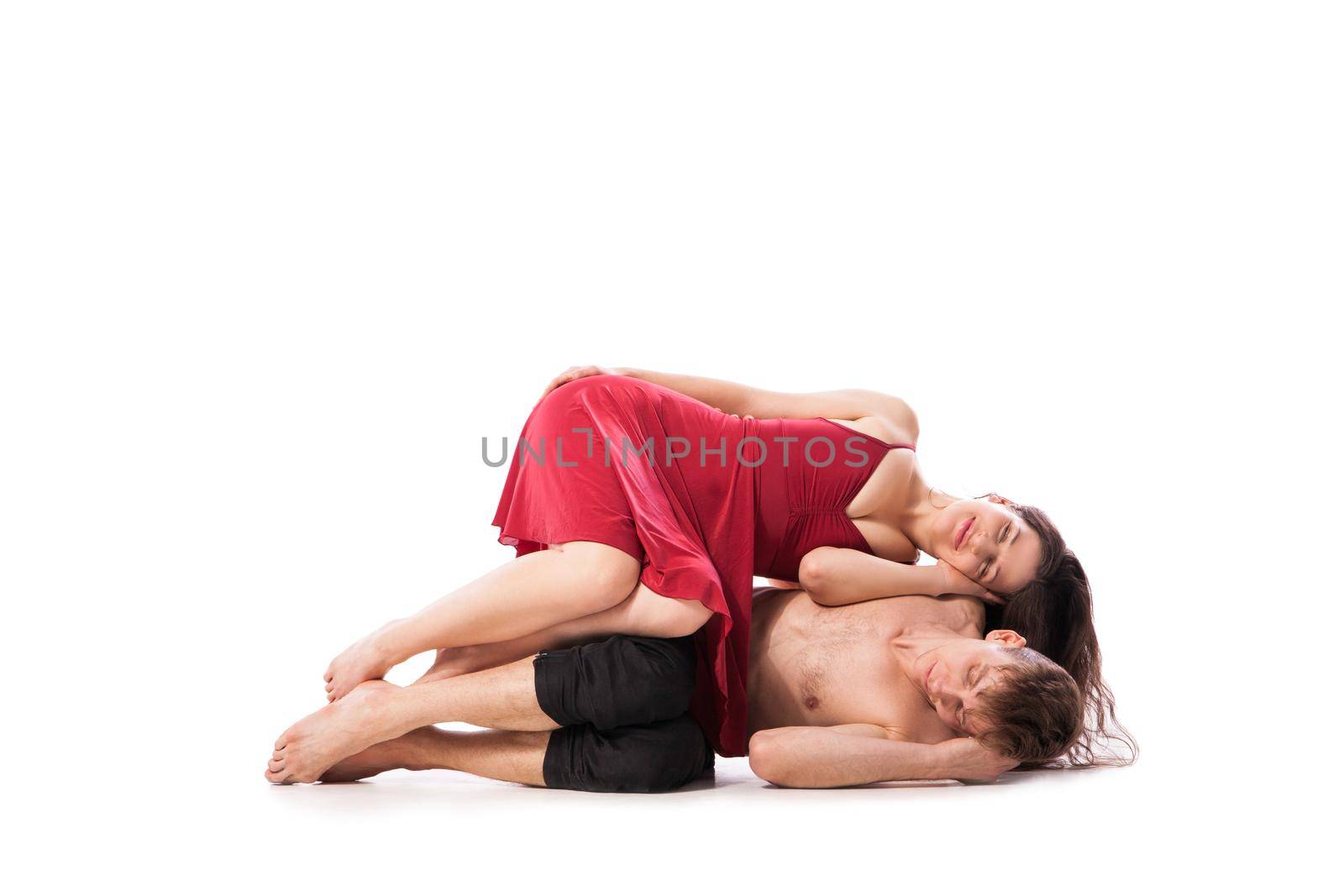 Woman dressed in pajamas laying on man. Isolated horizontal studio shot