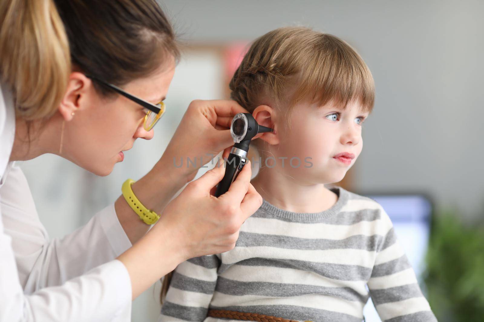 ENT doctor conducts physical examination of little girl ear by kuprevich