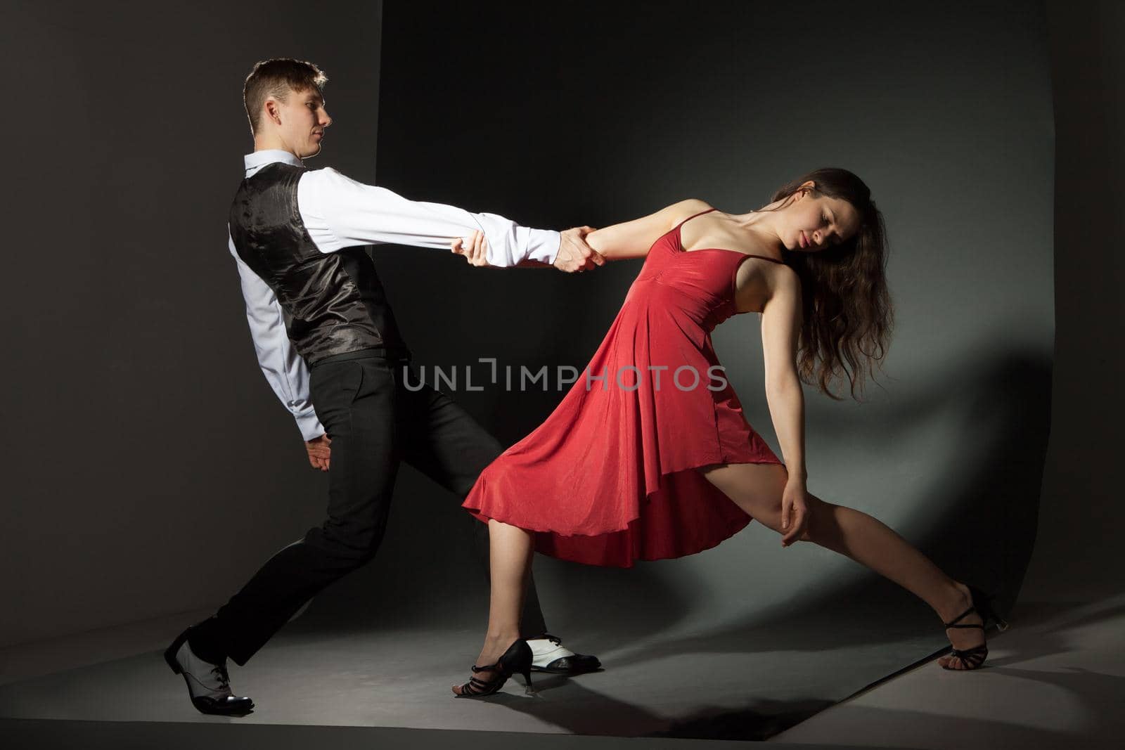 A pair holding each other while dancing. Horizontal studio shot