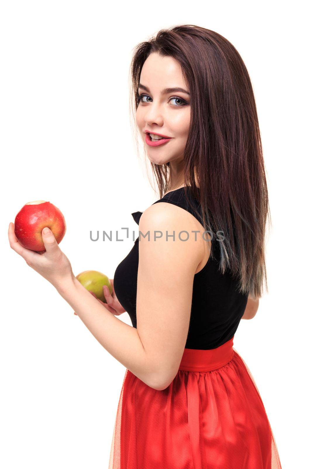 Beautiful young smiling woman holding an apple in her hands on a white background isolation. Bright brunette in black and red dress on a white background