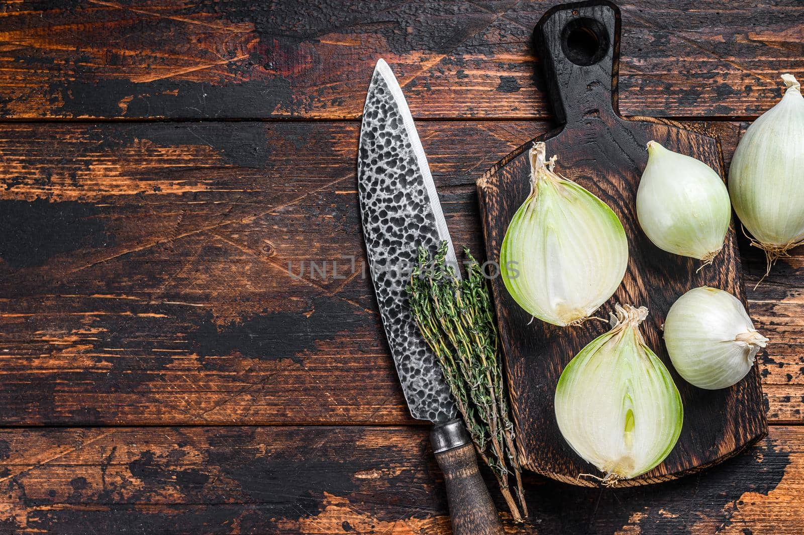 Raw fresh cut white onion on a wooden cutting board. Dark Wooden background. Top view. Copy space by Composter