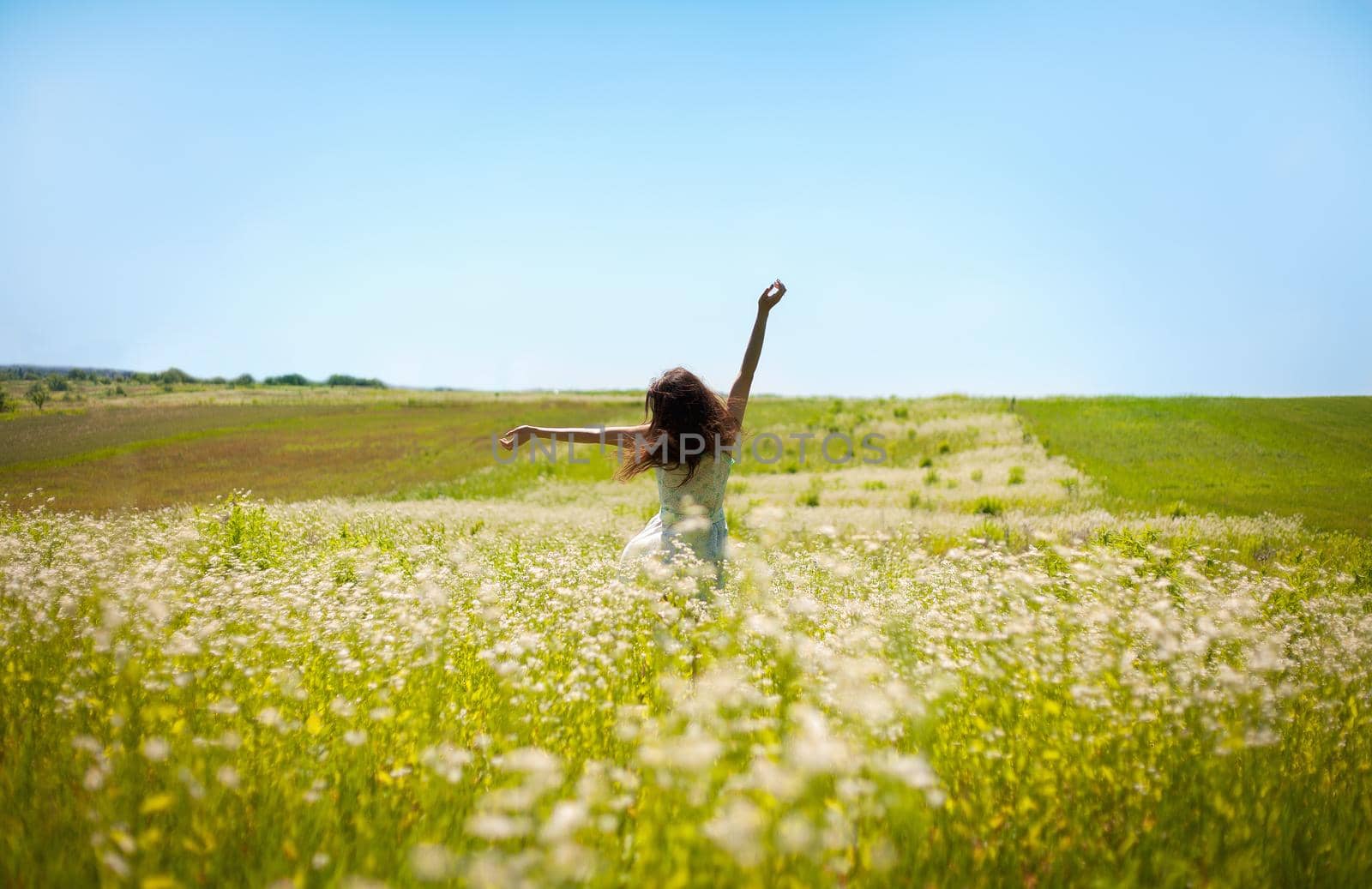 Girl lifting her hands up in the air runs across the field.