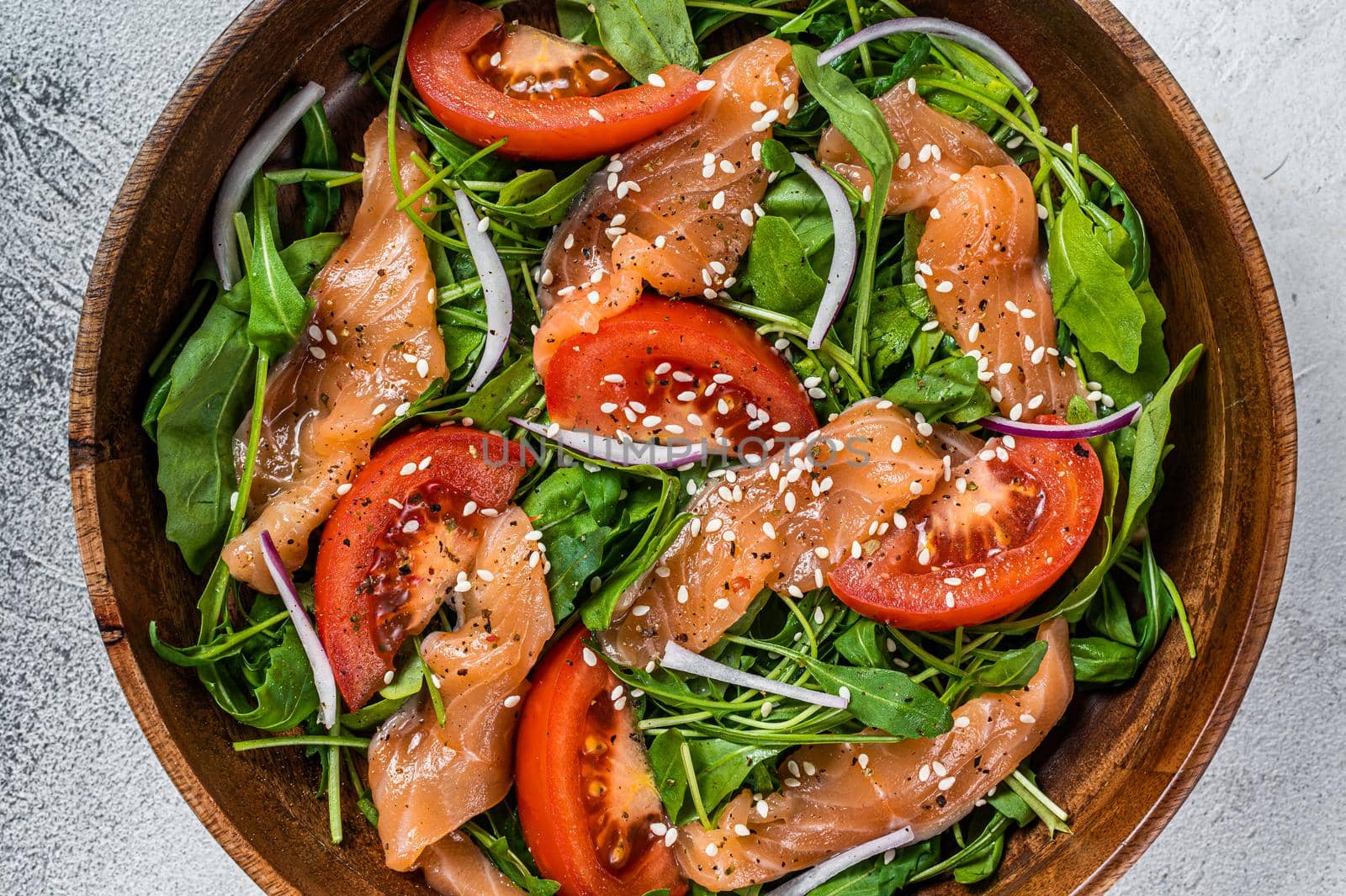 Smoked salmon salad with arugula, tomato and green vegetables. White background. Top View.