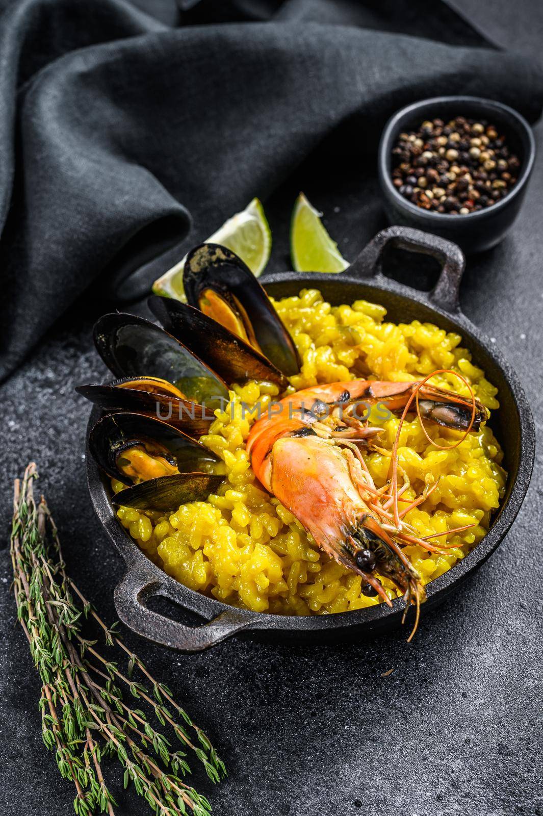 The Spanish paella with seafood prawns, shrimps, mussels. Black background. Top view by Composter