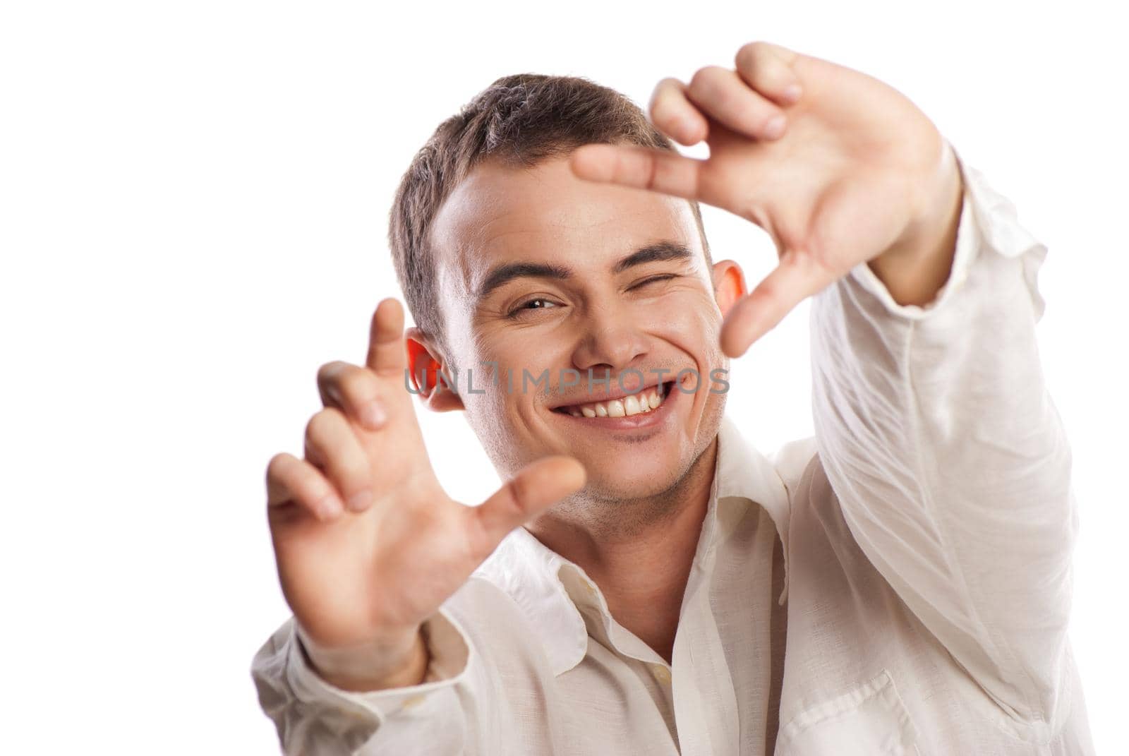 Portrait of smiling young man making frame with finger against white background