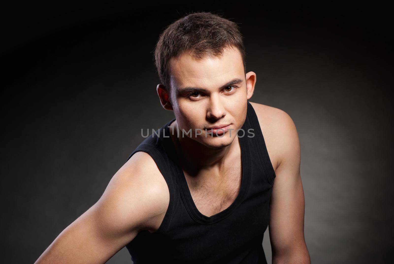 Closeup portrait of a sexy male model on dark grey background