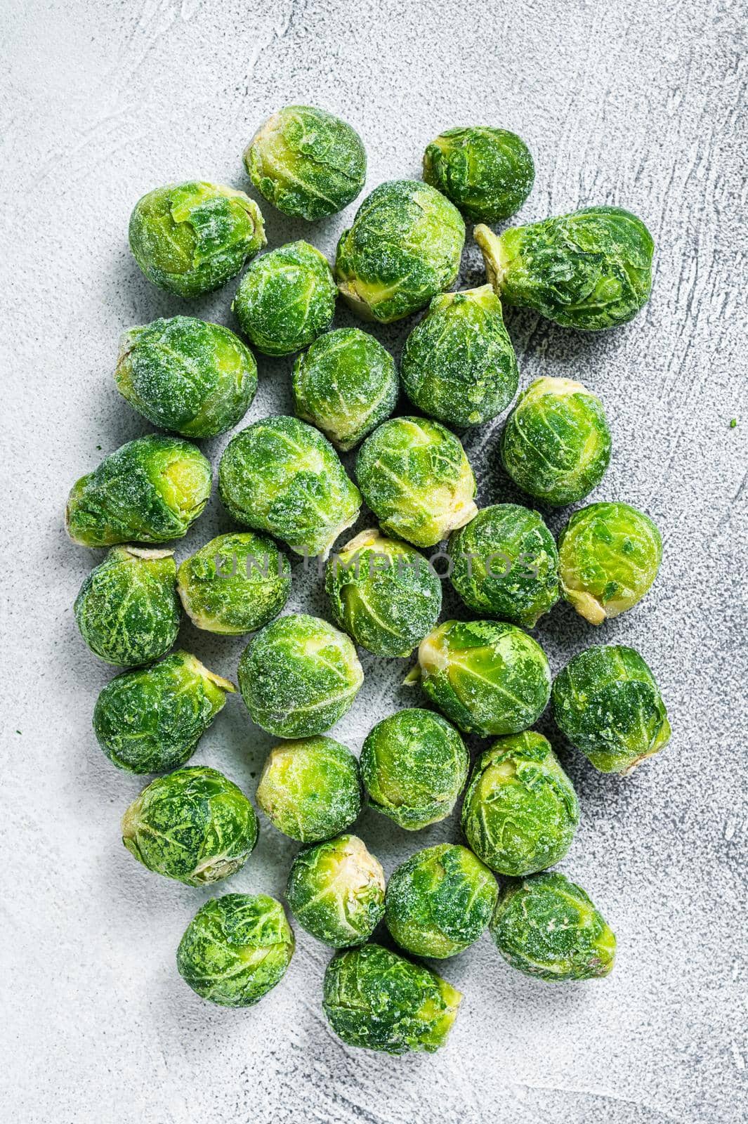 Frozen Brussels sprouts green cabbage on kitchen table. White background. Top view by Composter