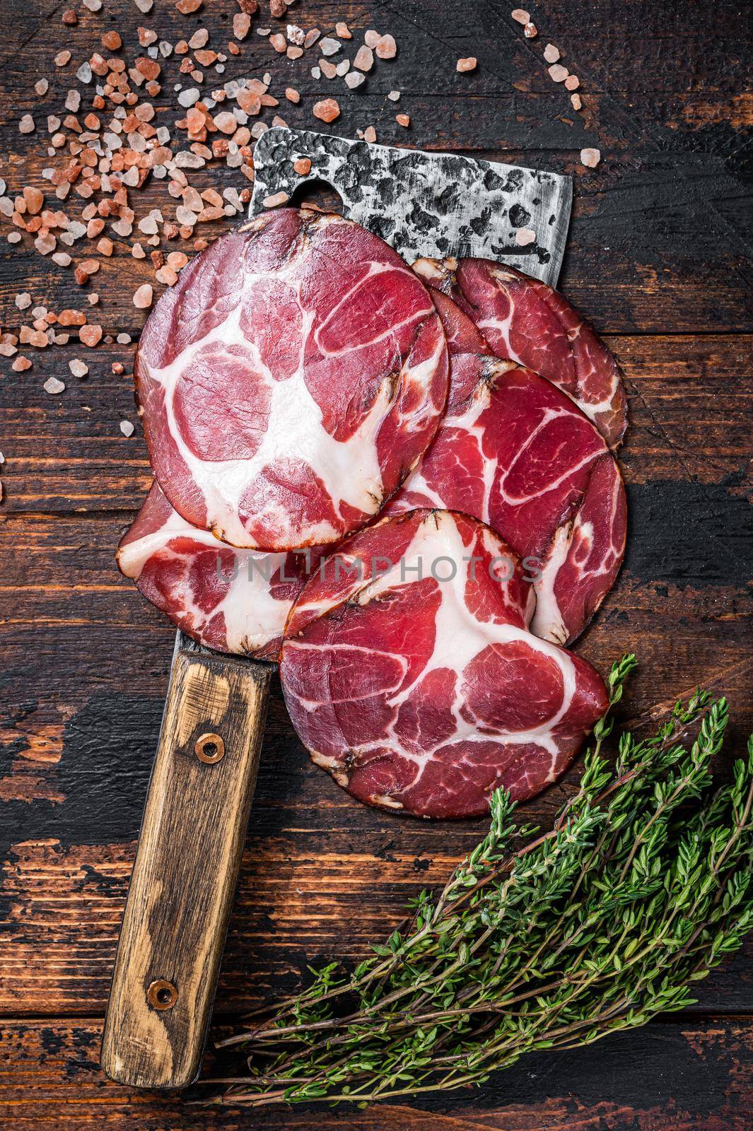 Coppa, Capocollo, Capicollo Cured ham on meat cleaver. Dark wooden background. Top view.