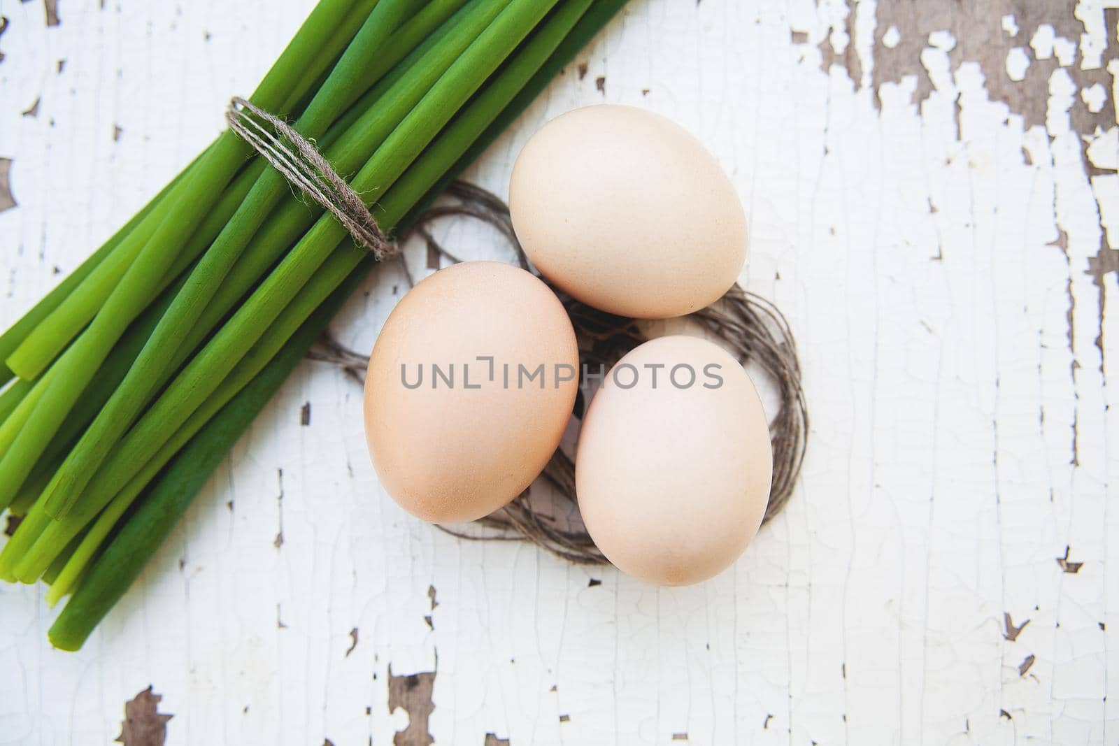 Spring onions and eggs lie on an old white table
