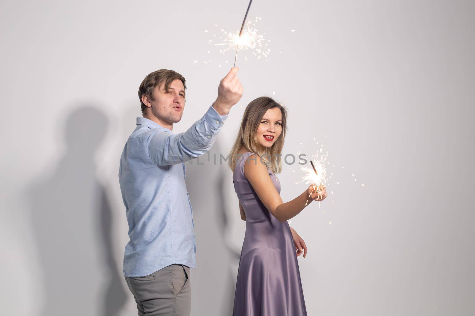 Holidays, party and celebrations concept - young couple with sparklers on white background by Satura86