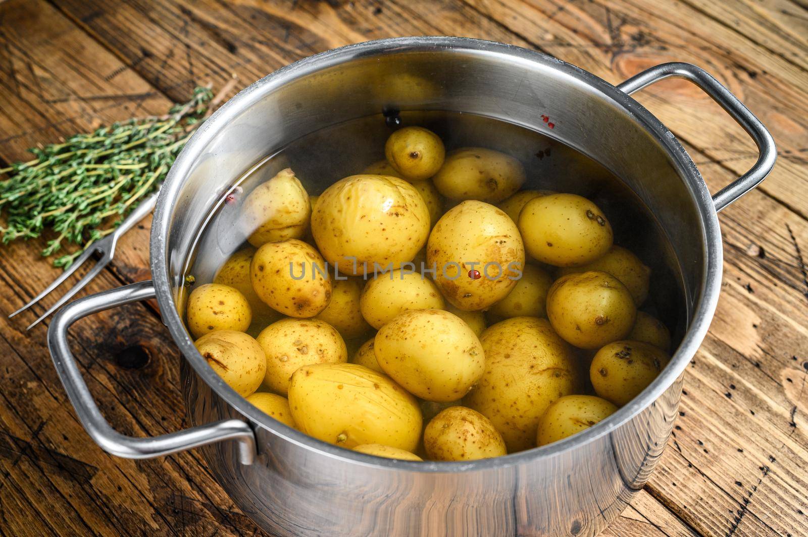 Boiled baby Potatoes in a saucepan. Wooden background. Top view by Composter