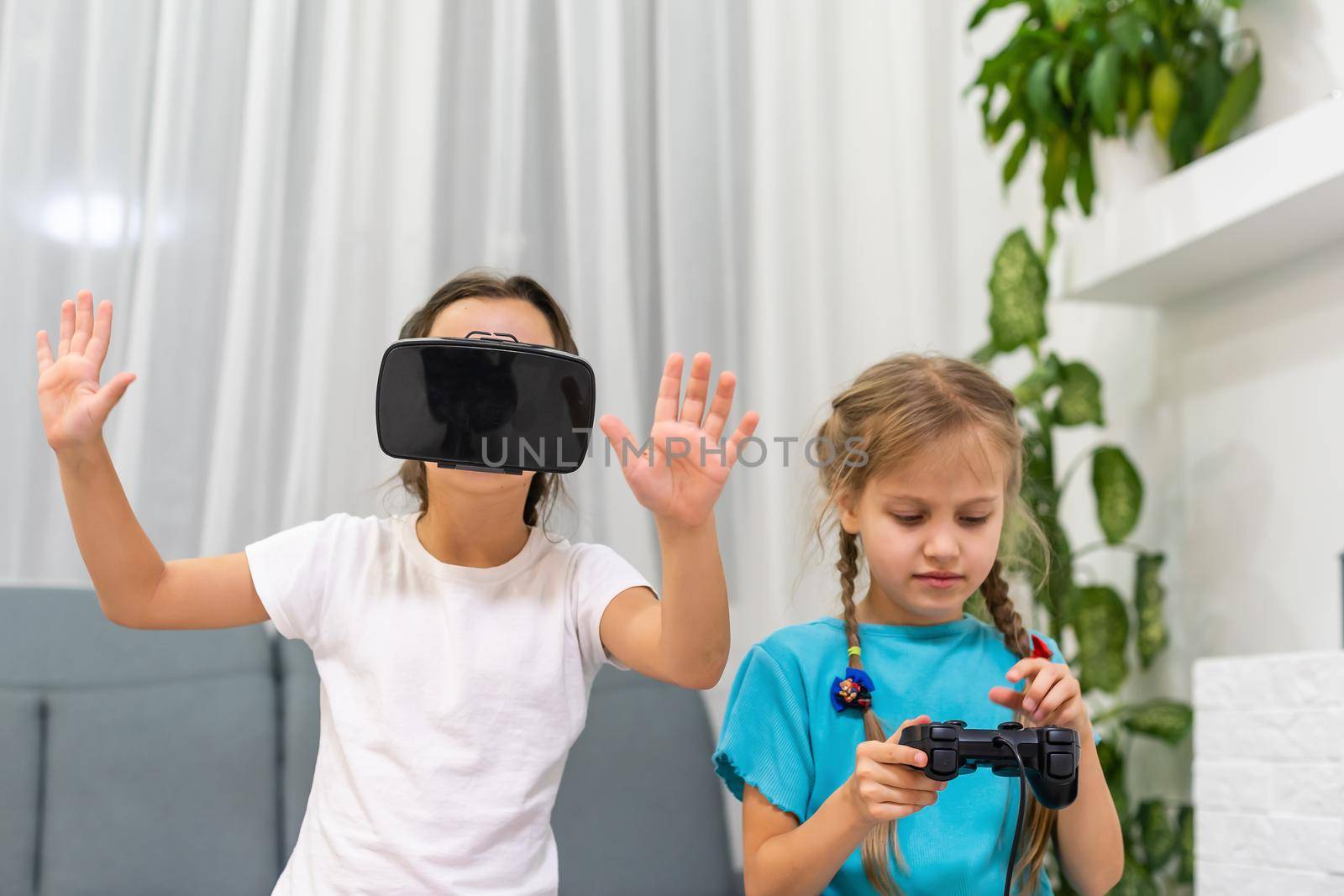 two little girls using glasses of virtual reality headset. concept of modern technologies by Andelov13