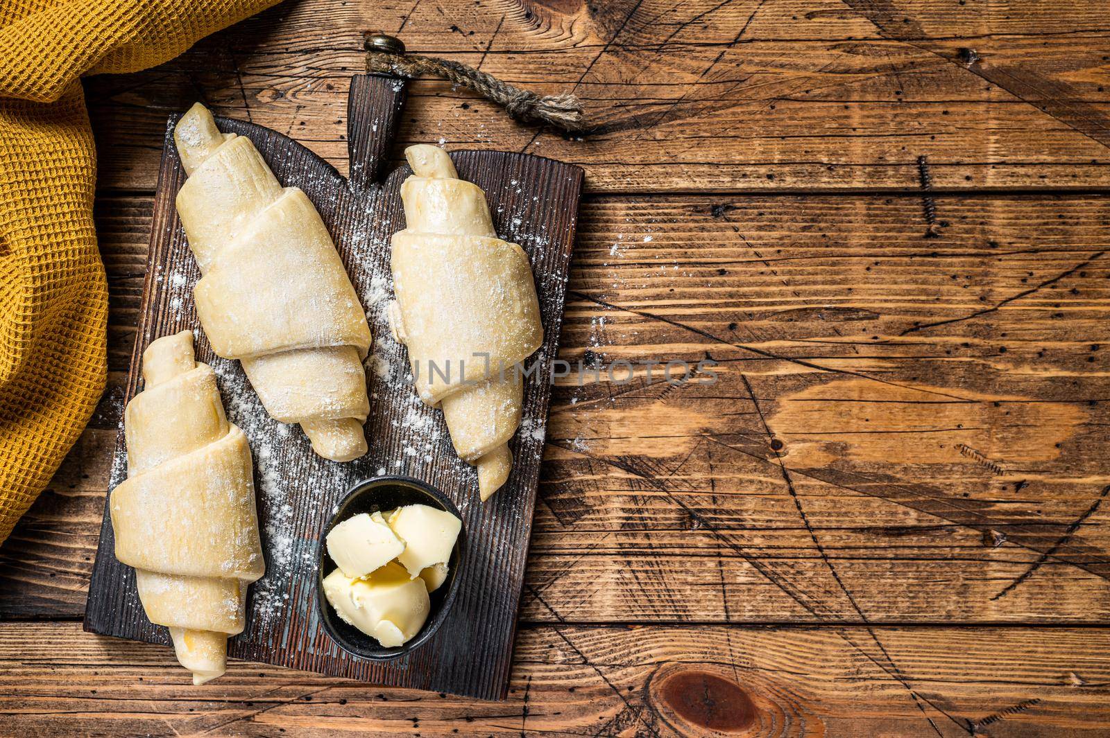 Raw uncooked french croissant on a wooden board. Wooden background. Top view. Copy space.