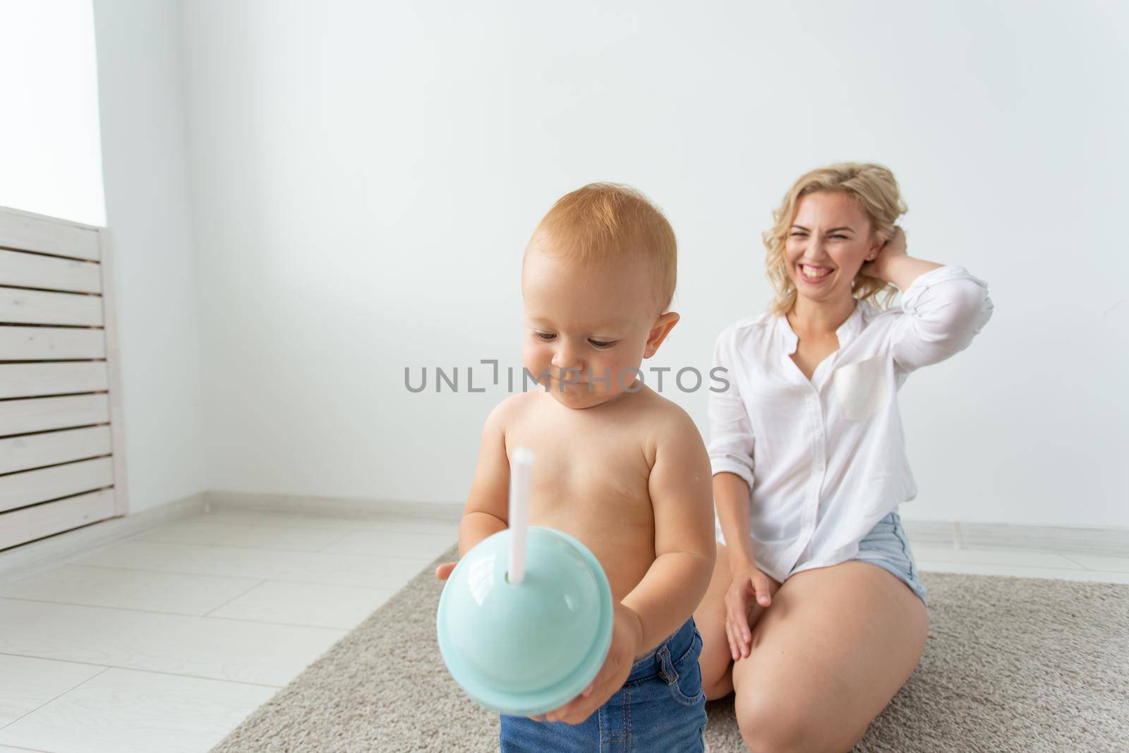 Family and parenting concept - Cute baby playing with her mother on beige carpet.