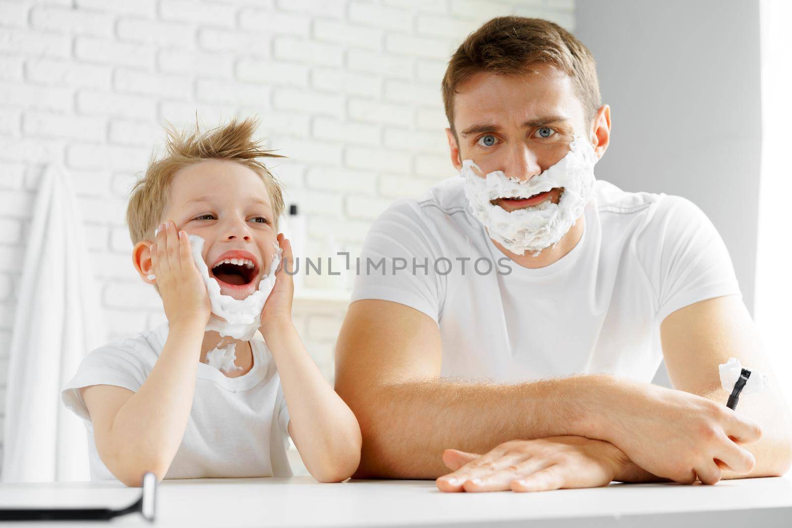 Father and little son having fun with shaving foam in bathroom